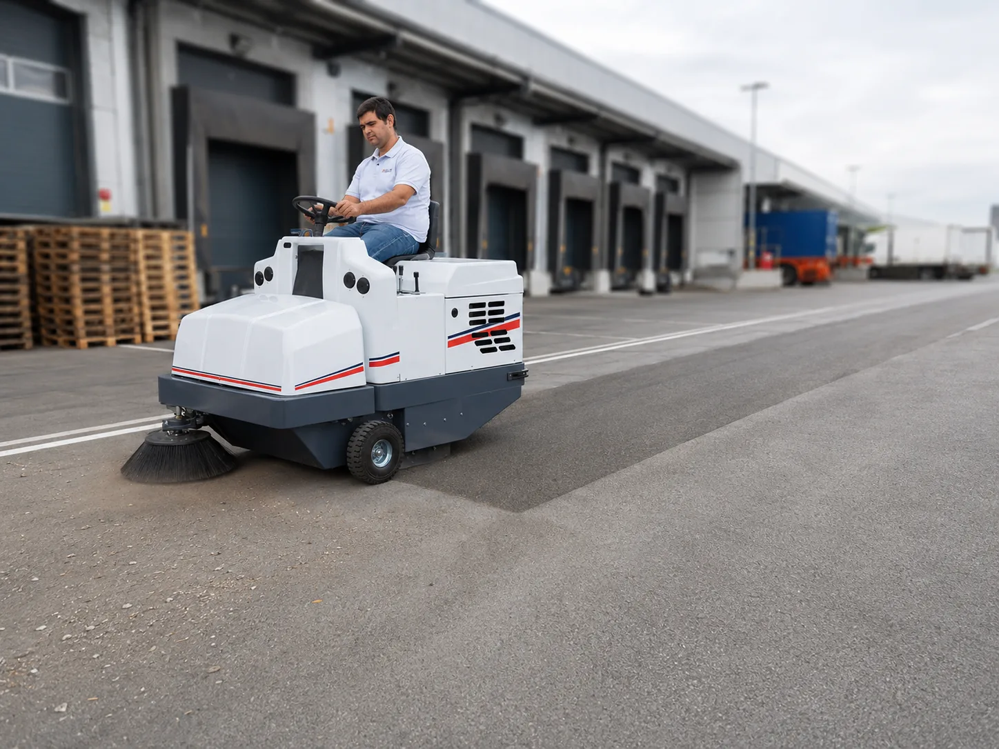 Măturătoare industrială DULEVO 1100 curățând platforma asfaltată a unui centru logistic, lângă porțile de andocare