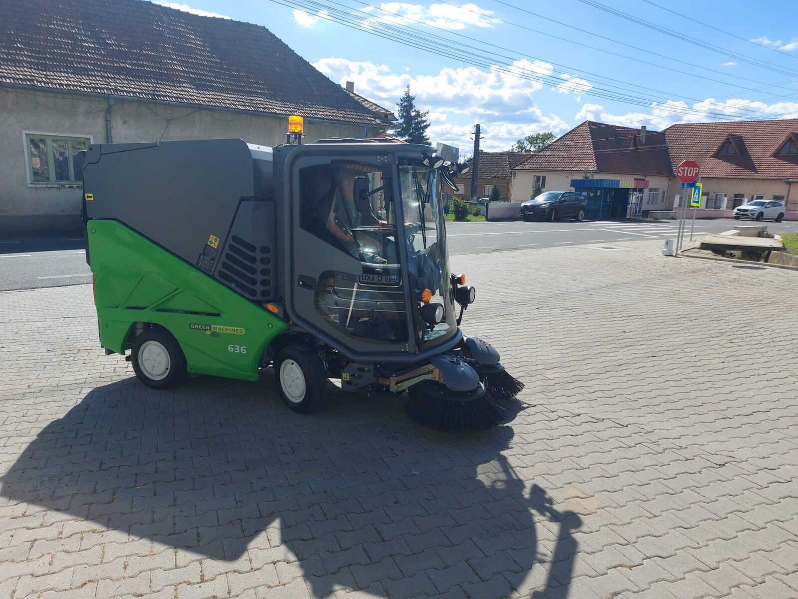 Green Machines 636 pe pavajul unei piețe, în fața unor case